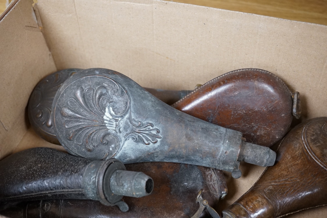 Three gun-sized copper powder flasks, two of which are embossed, together with four leather shot bags each with sprung chargers, two iron and two brass examples, one of which is embossed with a hunting scene (7)
